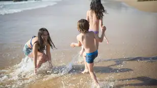 Niñas y niño jugando en la orilla de la playa
