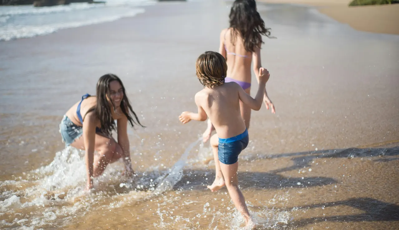 Niñas y niño jugando en la orilla de la playa