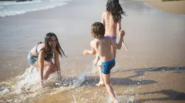 Niñas y niño jugando en la orilla de la playa